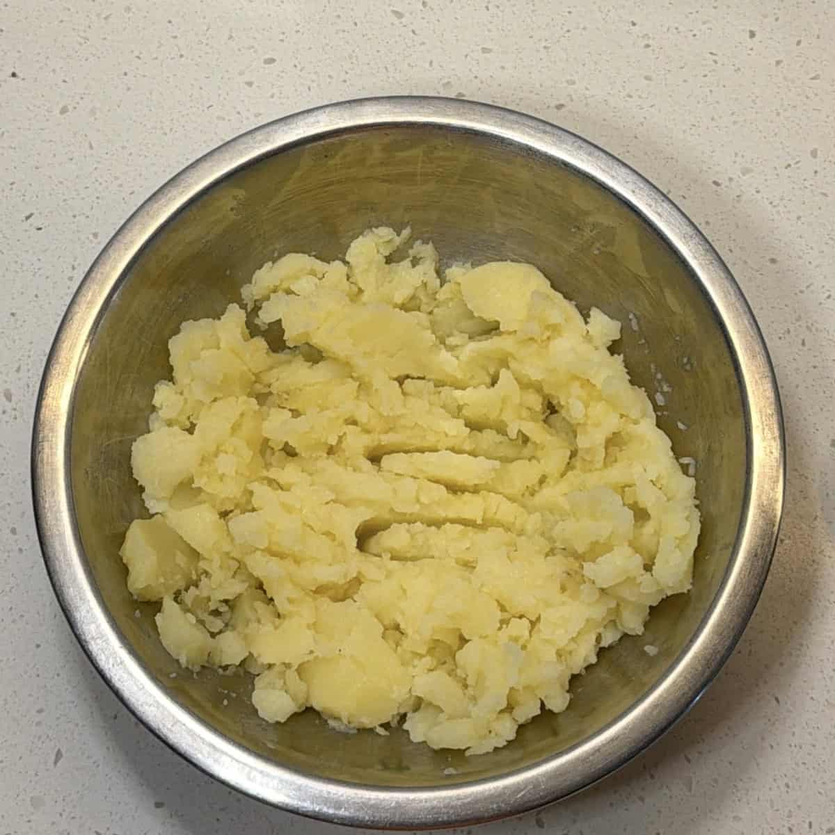 Boiled potatoes mashed in a steel bowl for stuffed bread roll filling