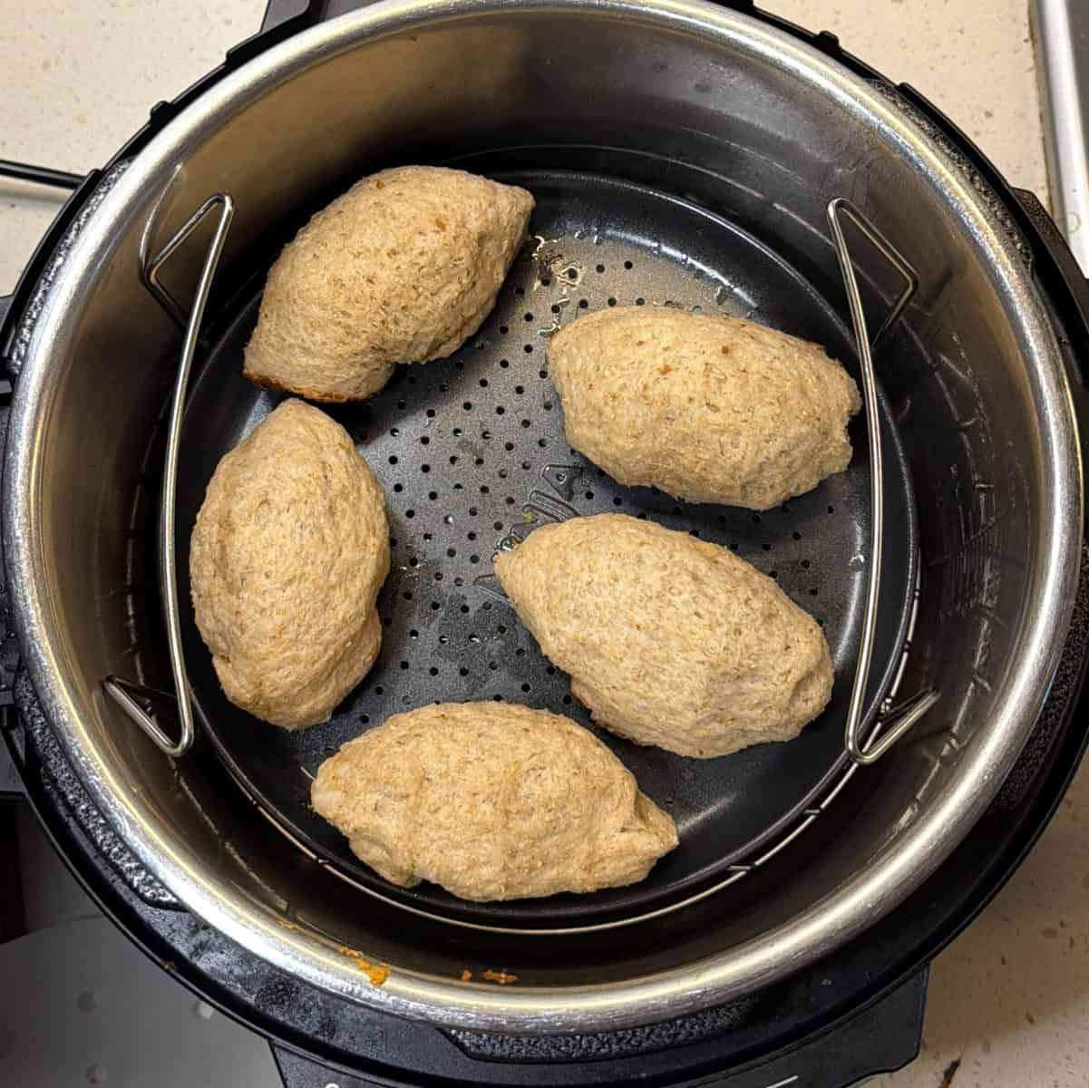 Uncooked stuffed bread rolls arranged in the air fryer basket