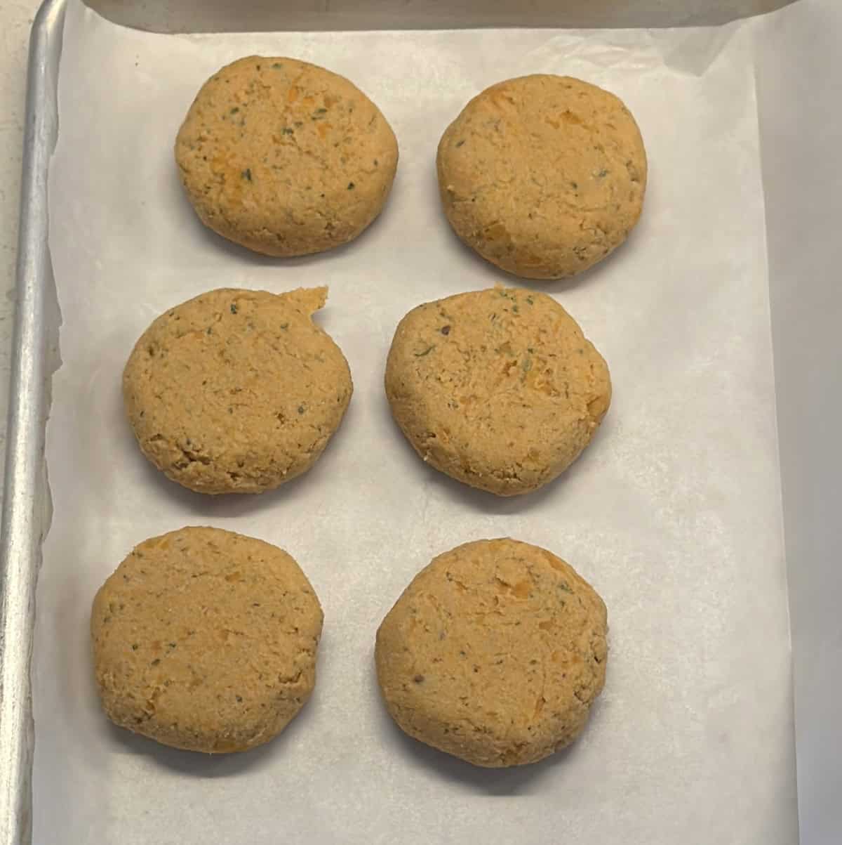 Raw cutlets layered with parchment in a tray before freezing