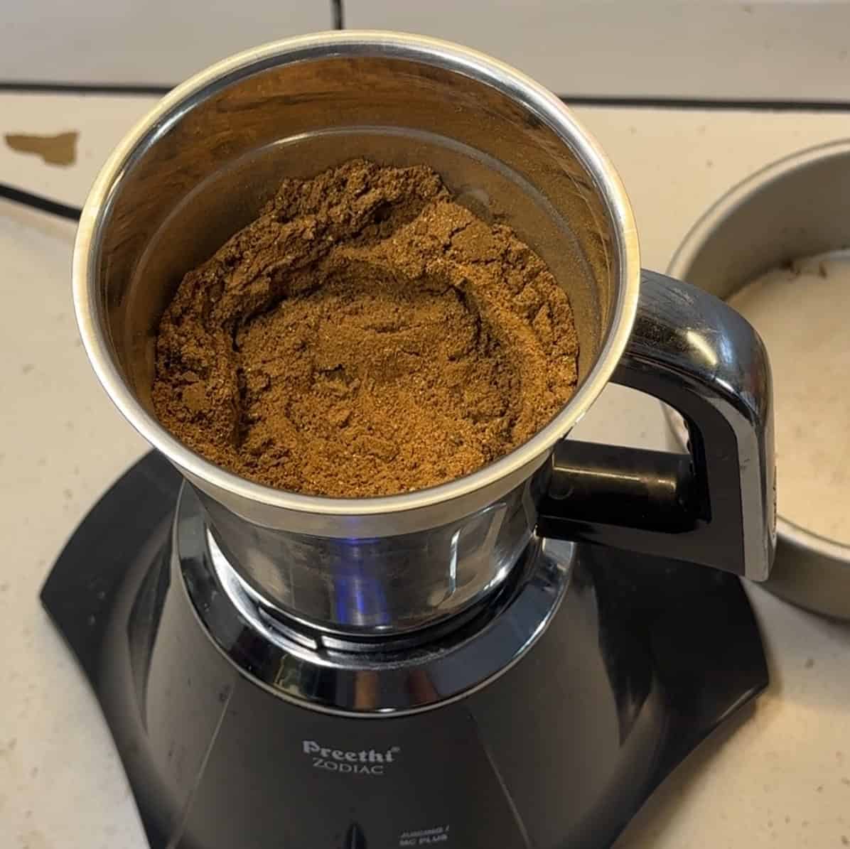 Finely ground garam masala powder in a spice grinder jar.