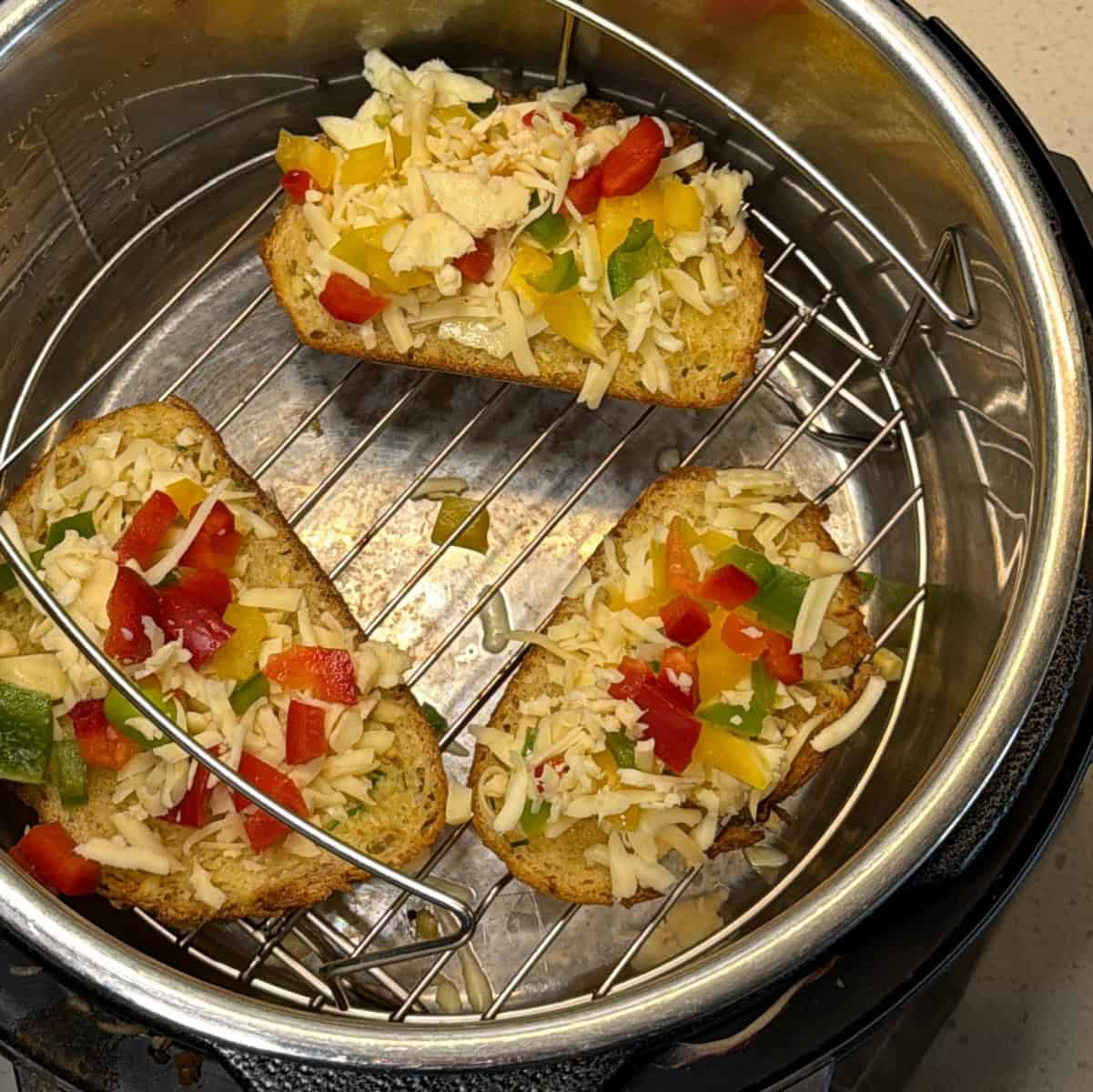 Bread slices with garlic spread placed in air fryer before toasting