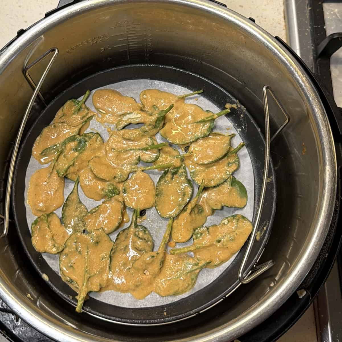 Place batter coated spinach leaves on air fryer tray lined with parchment, arrange leaves in single layer