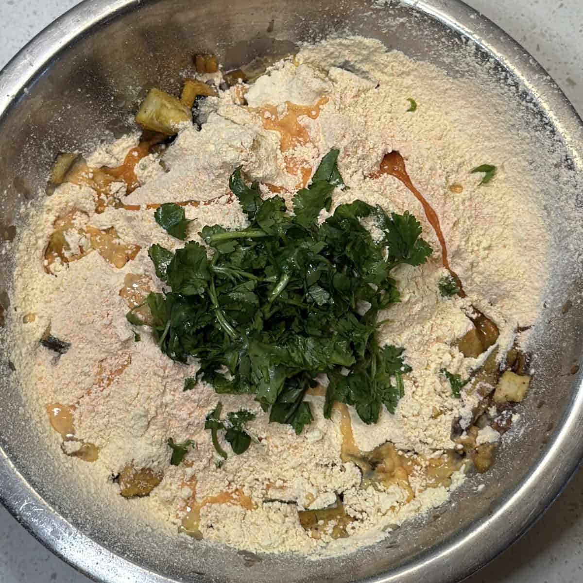 Red lentil flour, besan, and coriander added to chopped eggplant for baingan pakora