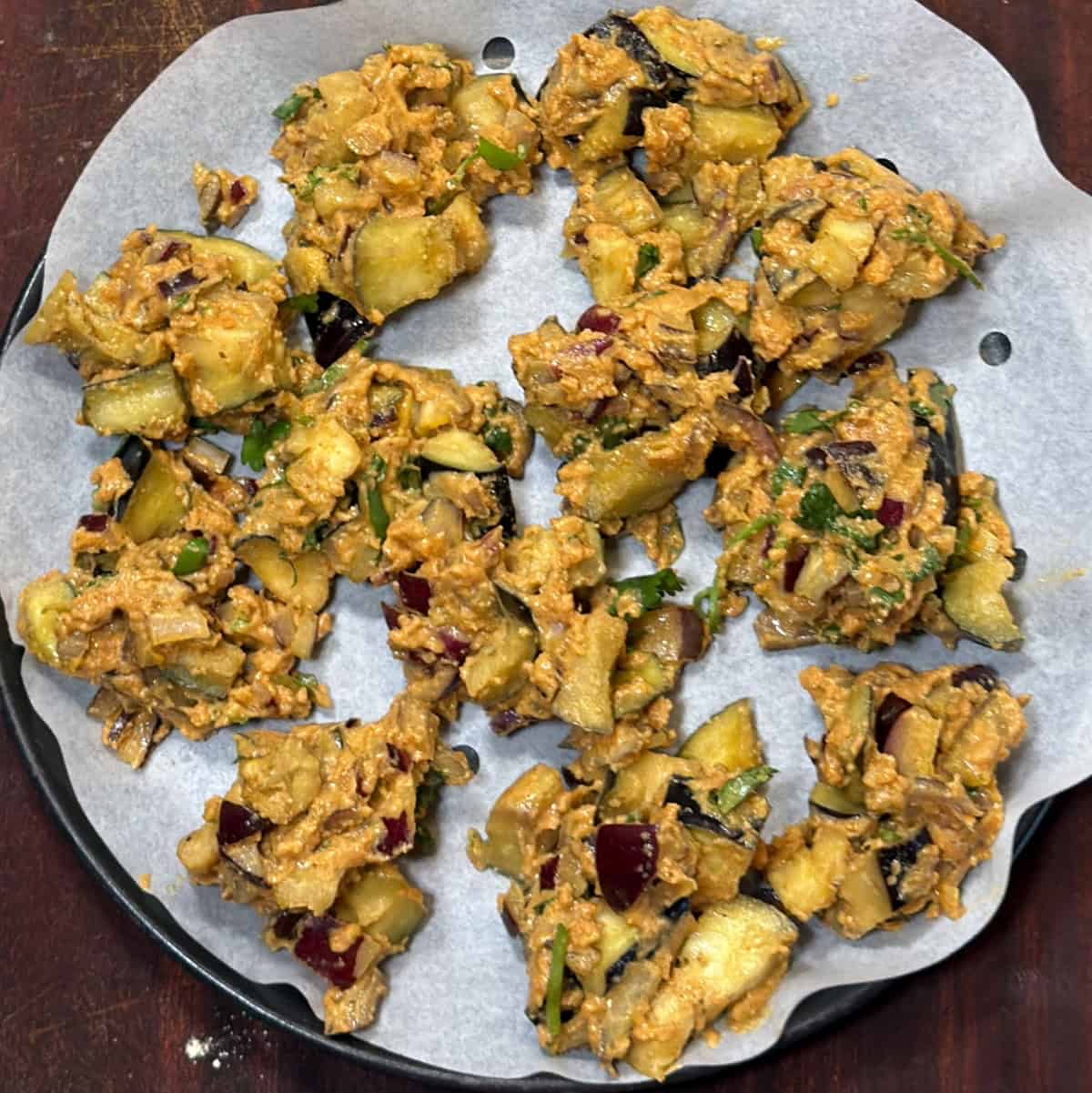 Raw eggplant pakora portions placed on parchment paper for air frying