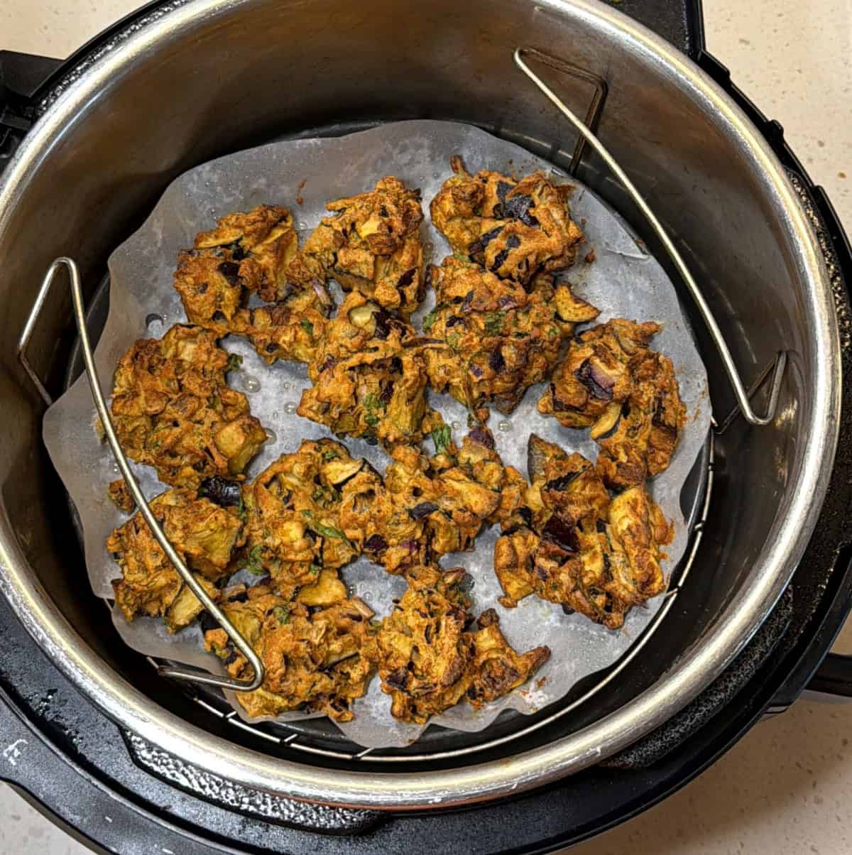 Air fryer eggplant pakora cooked on parchment paper until golden and crisp