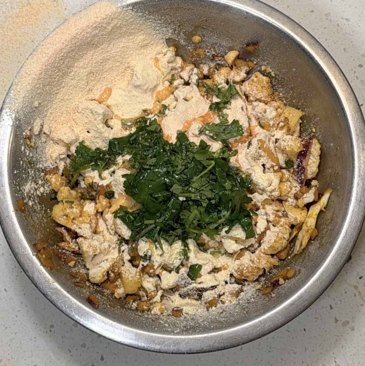 Red lentil flour besan and coriander added to cauliflower pakora mixture