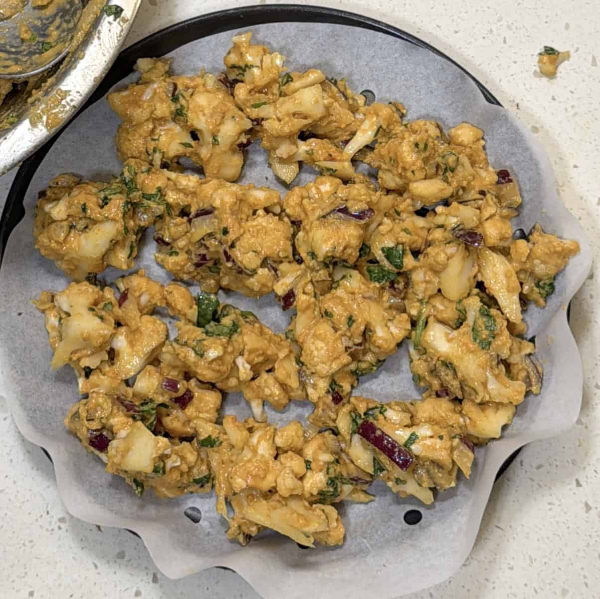 Cauliflower pieces coated with pakora batter before air frying