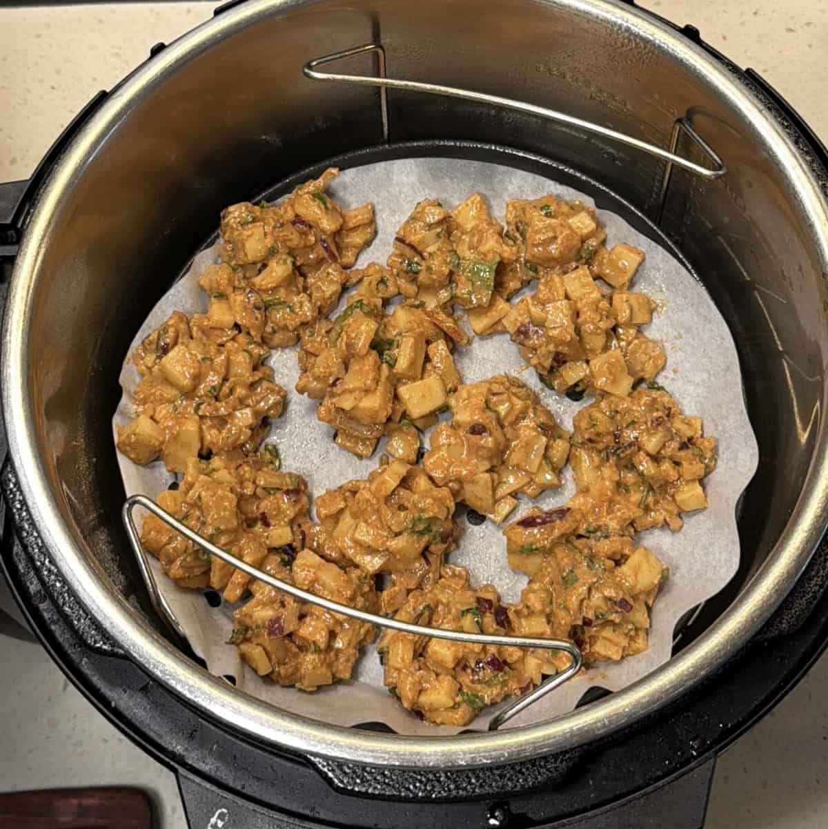 Potato pakora cooking in an air fryer basket