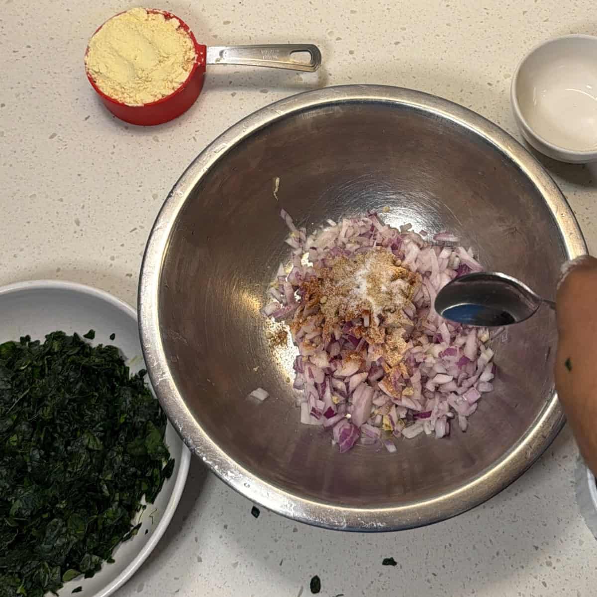 Onion ginger and spices mixed in a bowl for air fryer spinach pakora