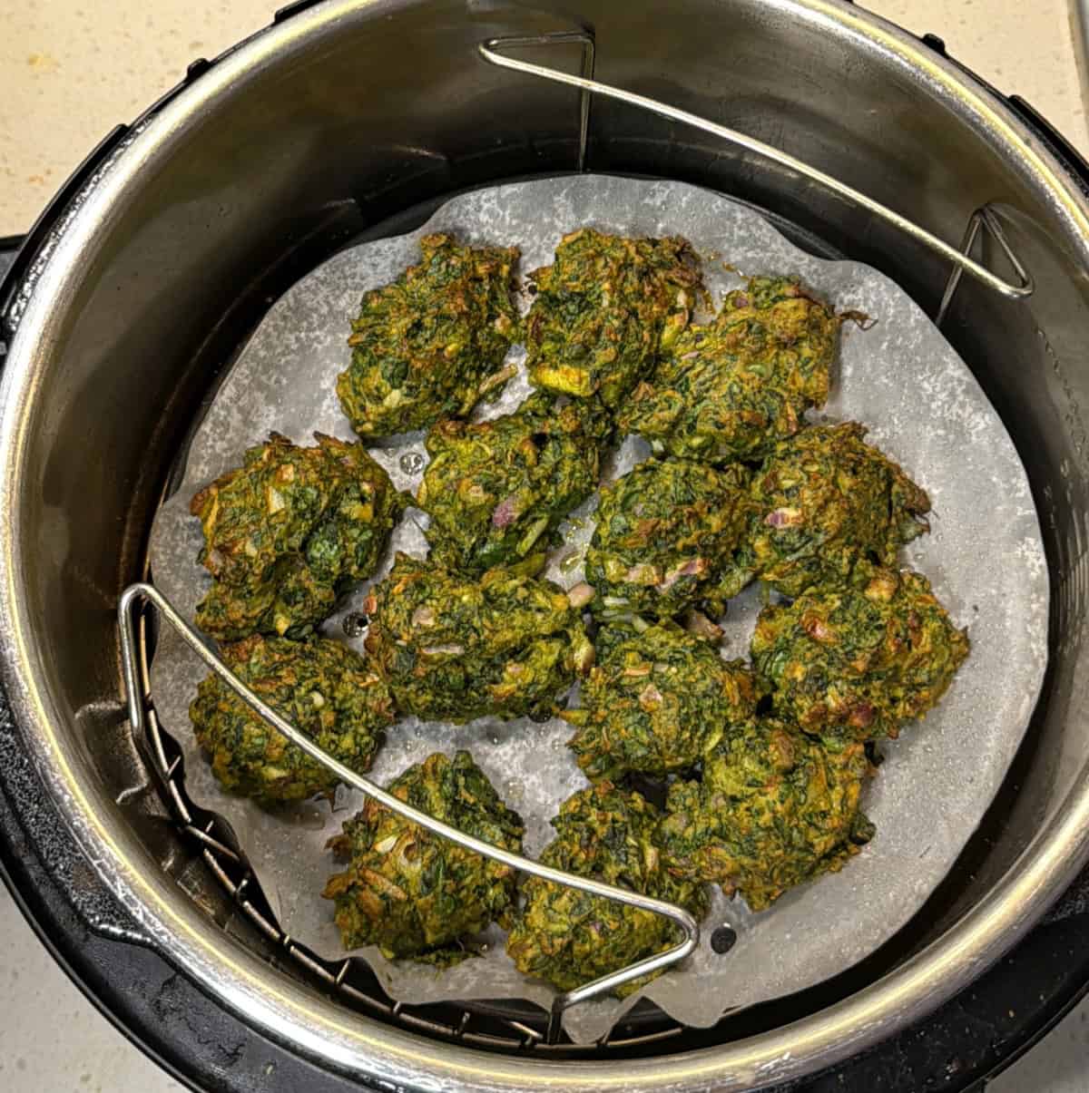 Spinach pakoras cooking in the air fryer until firm and lightly golden