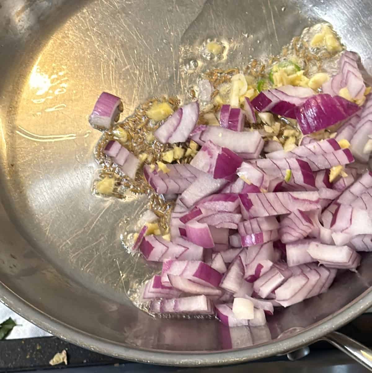 Chopped onion and ginger cooking in oil for air fryer paneer puffs