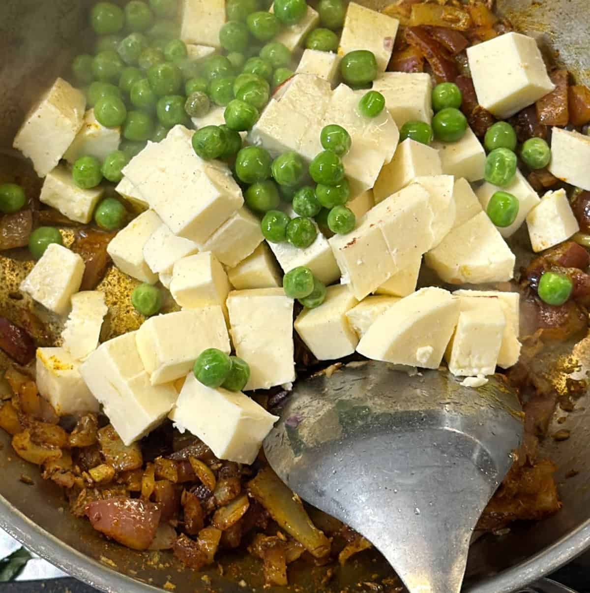 Paneer cubes and green peas added to onion masala for paneer puff filling