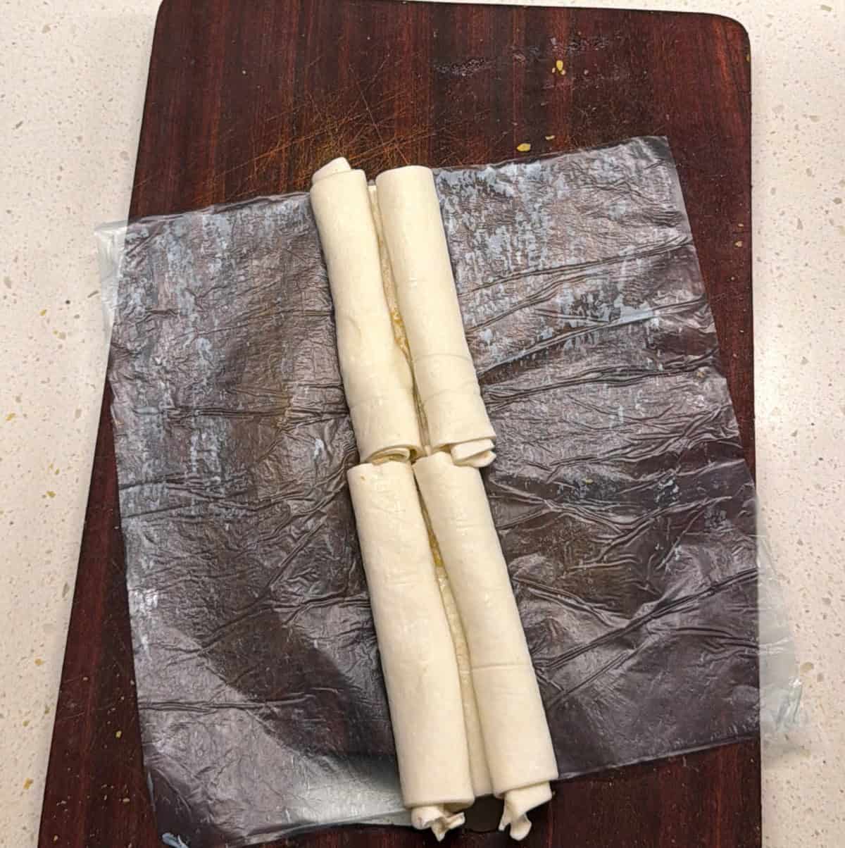 Seasoned puff pastry squares rolled into logs for vegan pastry twists
