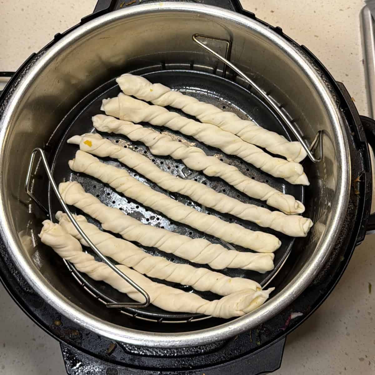 Vegan puff pastry twists arranged in air fryer basket before cooking