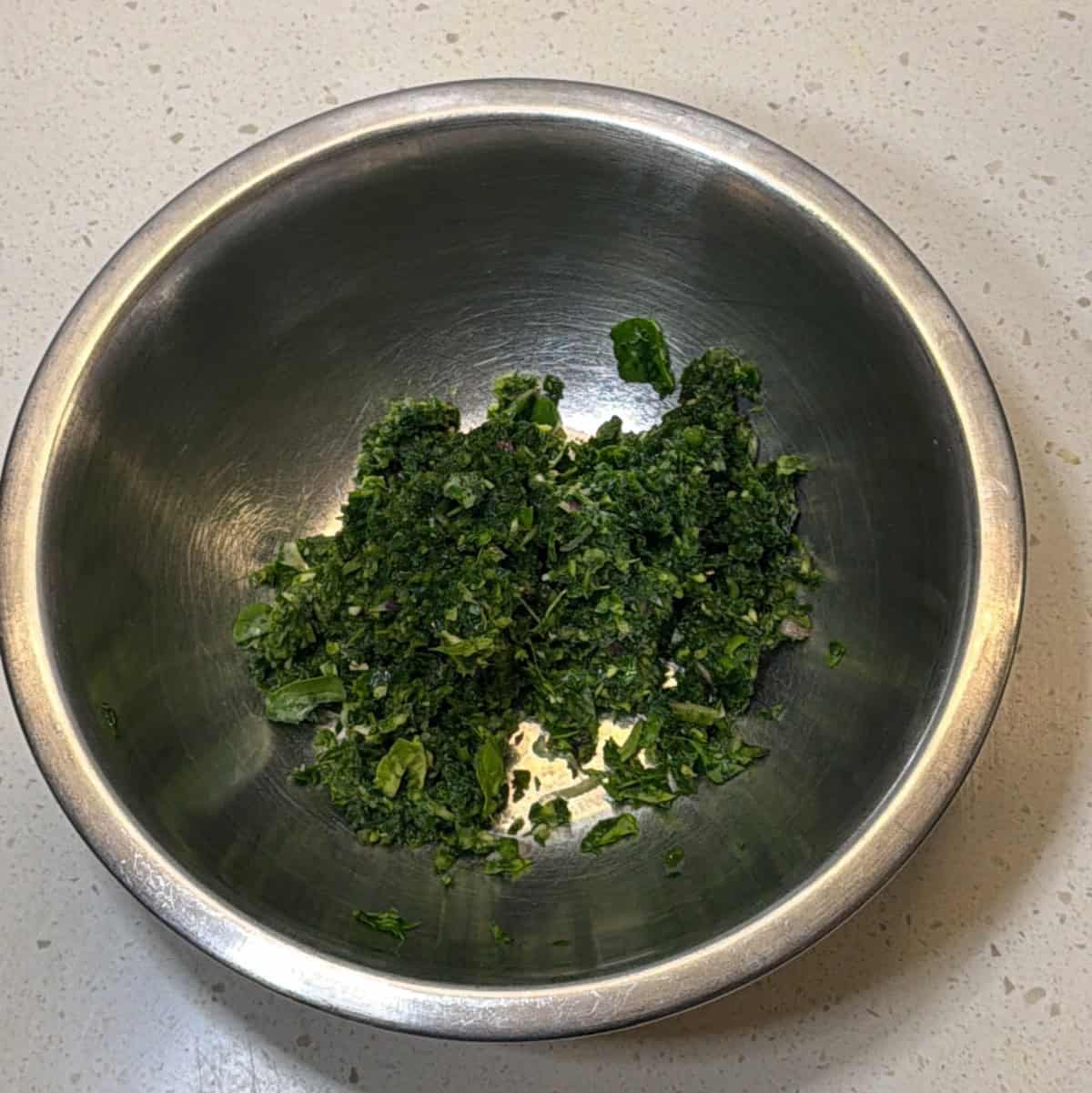 Coarsely chopped methi spinach and onion mixture in mixing bowl