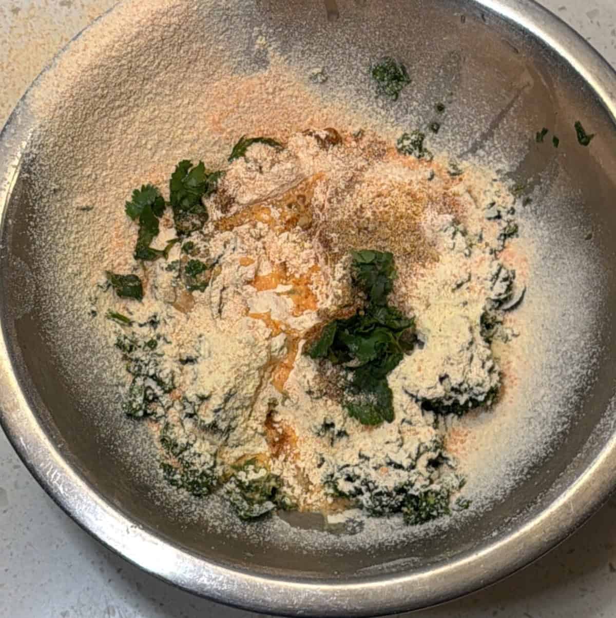 Red lentil flour chickpea flour and spices added to methi pakora mixture