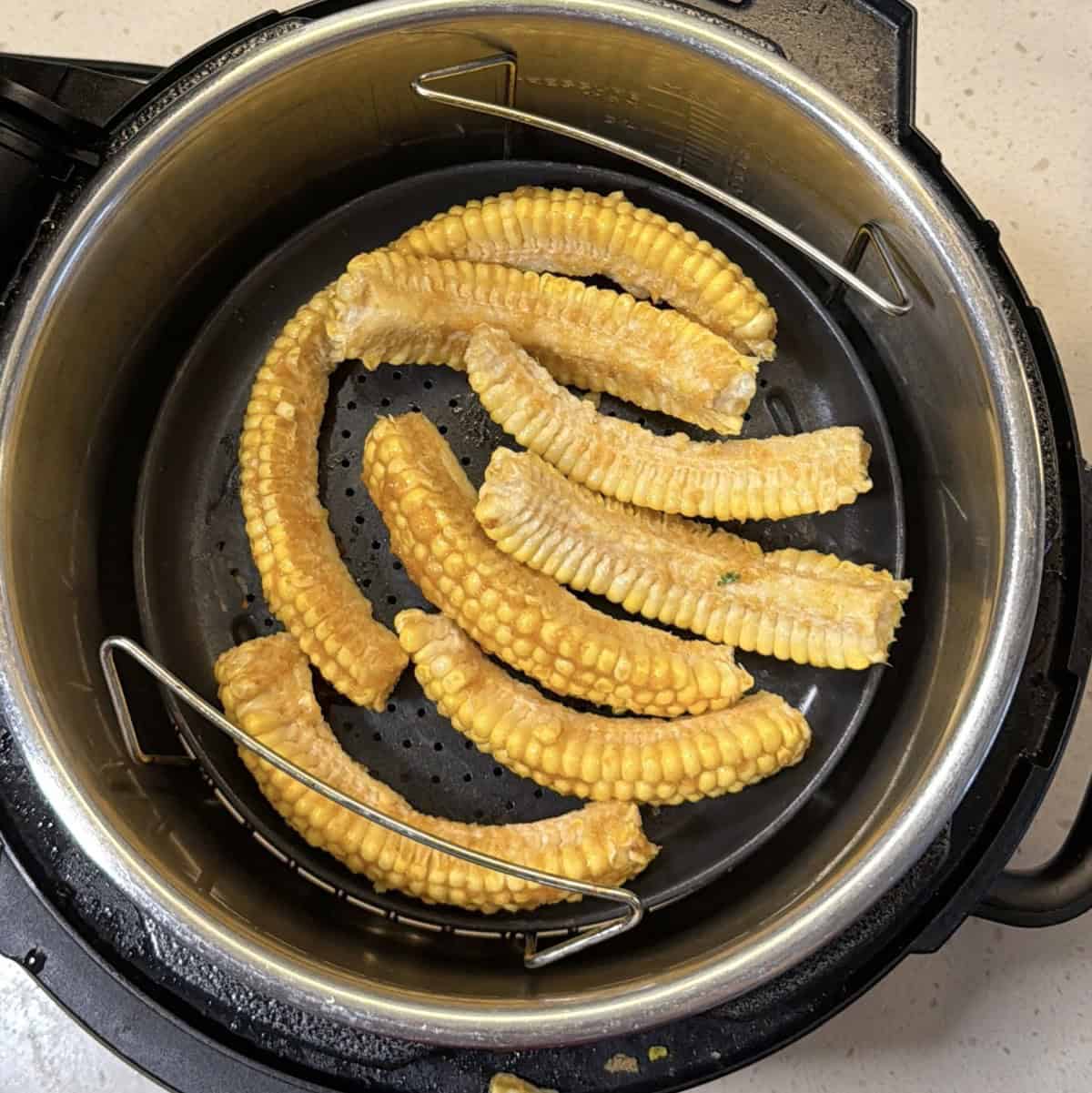 Coated corn ribs arranged in the air fryer basket before cooking