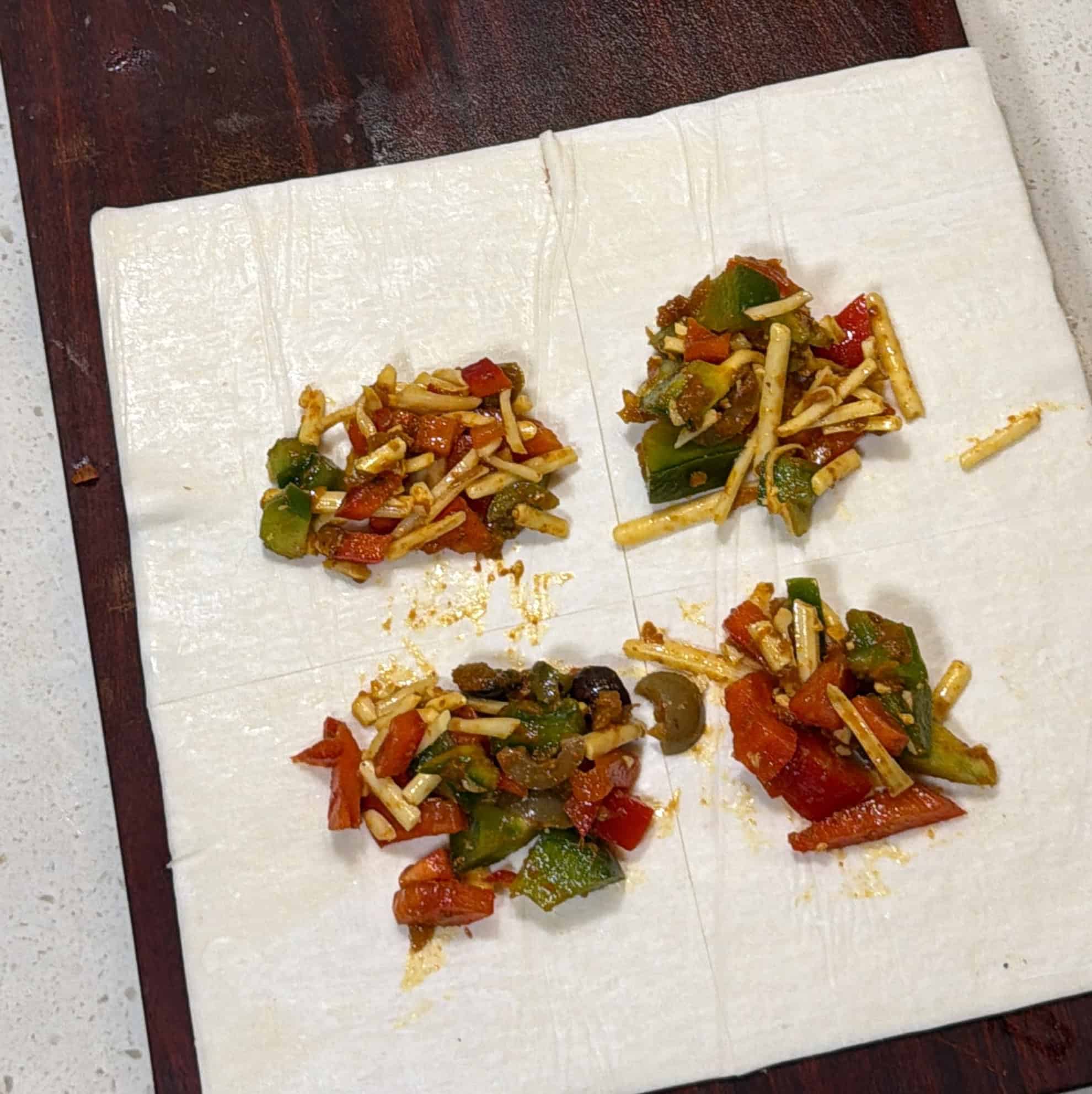 Pizza filling placed on puff pastry squares for air fryer pizza puffs