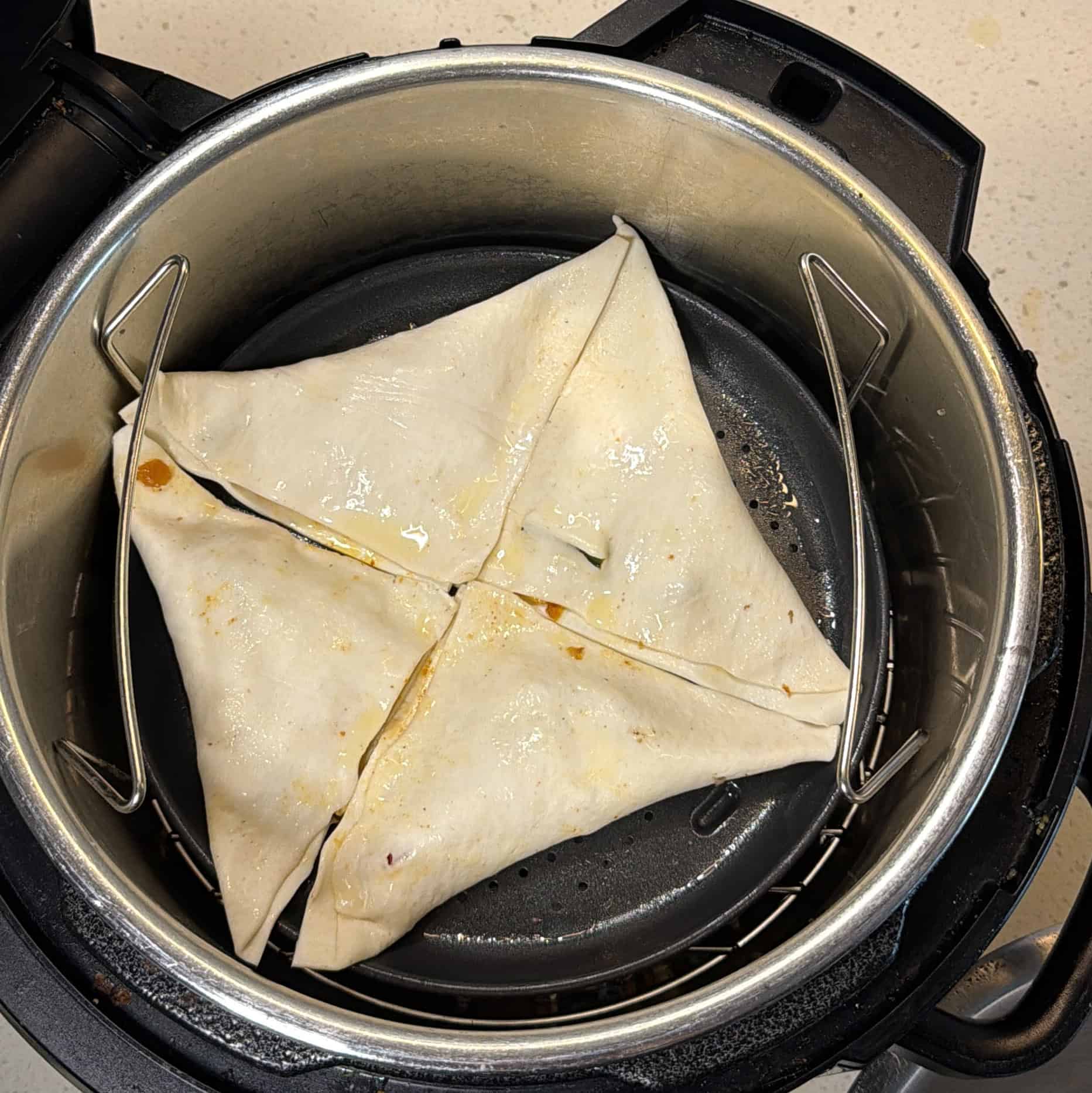 Uncooked pizza puffs arranged in the air fryer basket