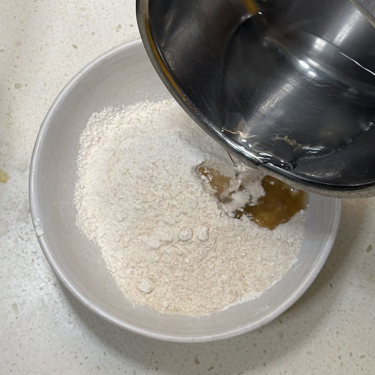 Hot water being added to powdered sugar for sattu burfi