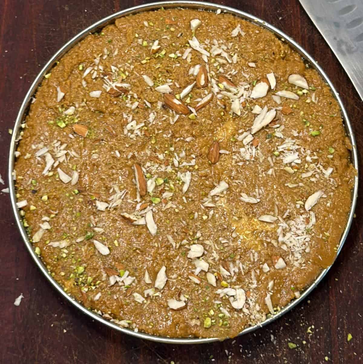 Sattu burfi set in greased tray with sliced almonds