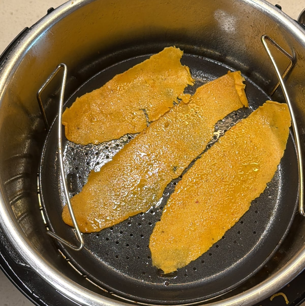 Fafda strips in air fryer basket brushed with oil