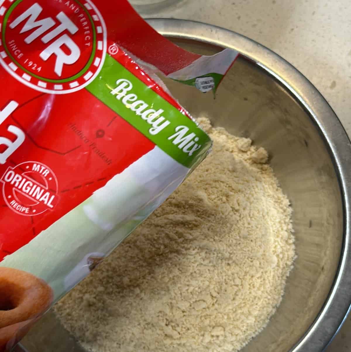 MTR instant medu vada ready mix being poured into a mixing bowl.