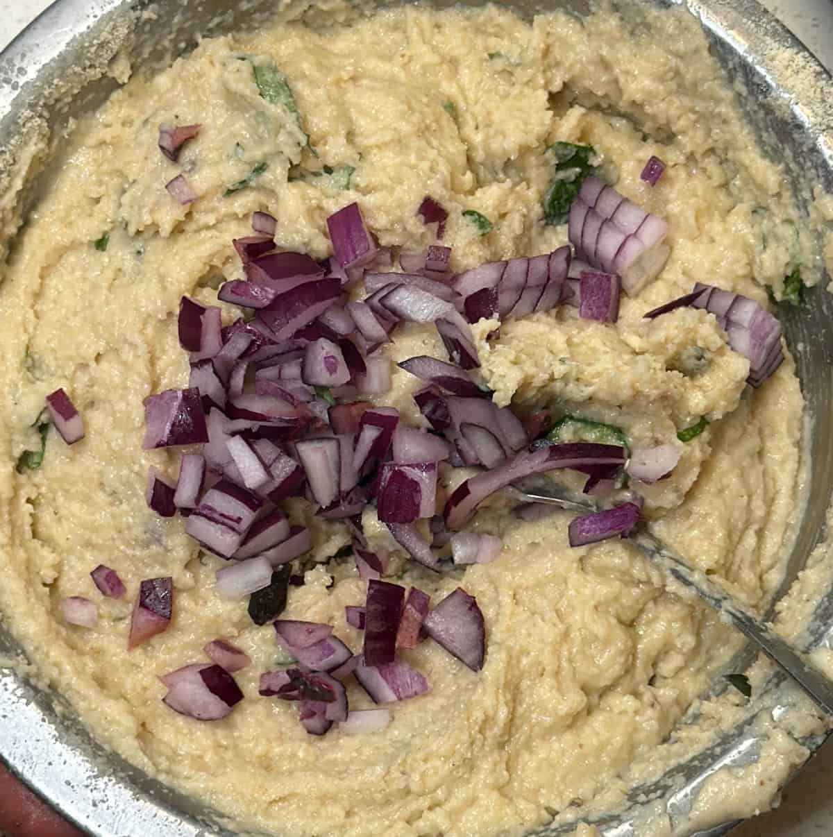 Thick medu vada ready-mix batter with chopped red onion and herbs.