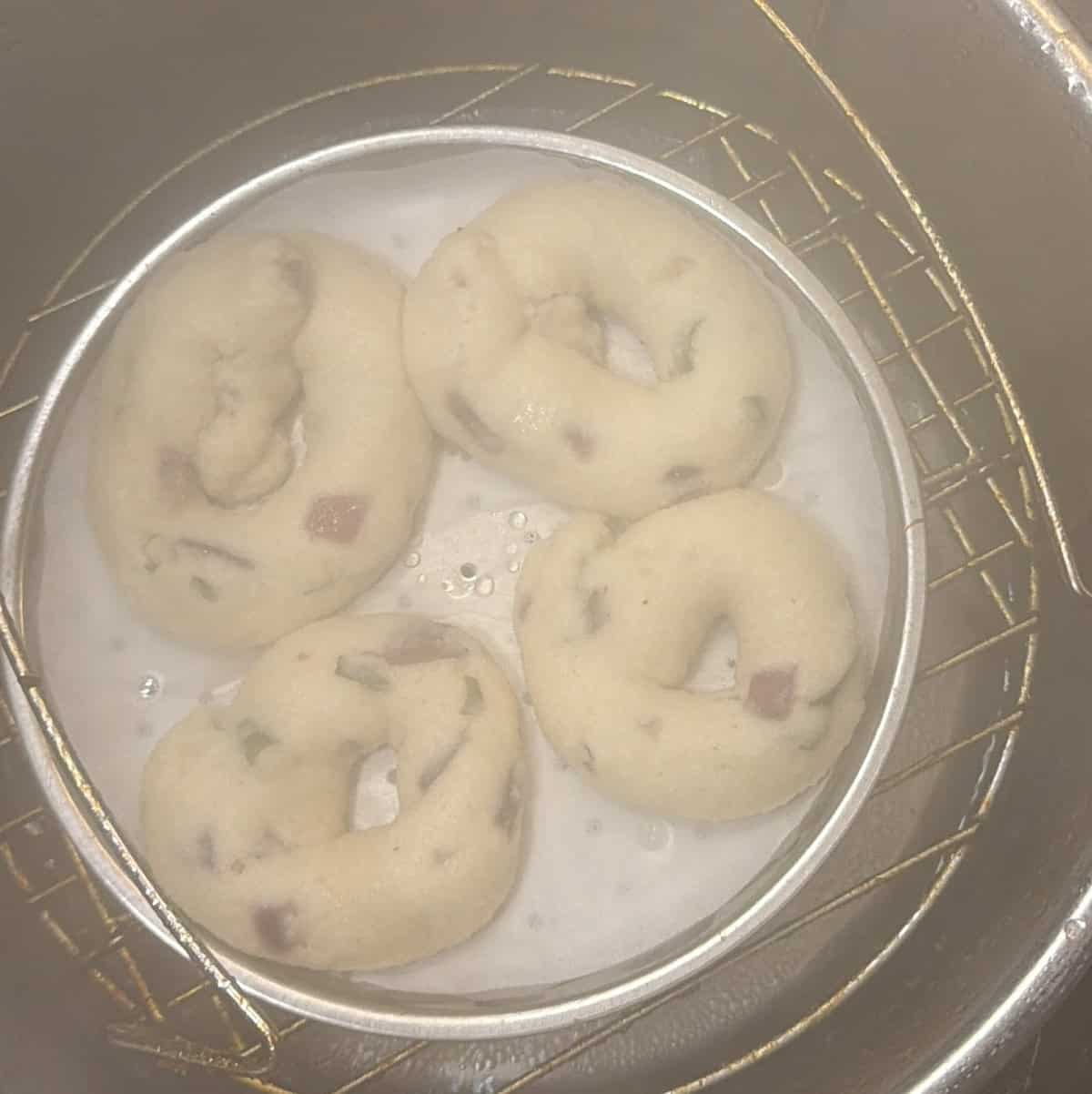 Instant medu vadas on a perforated parchment-lined tray in a steamer.