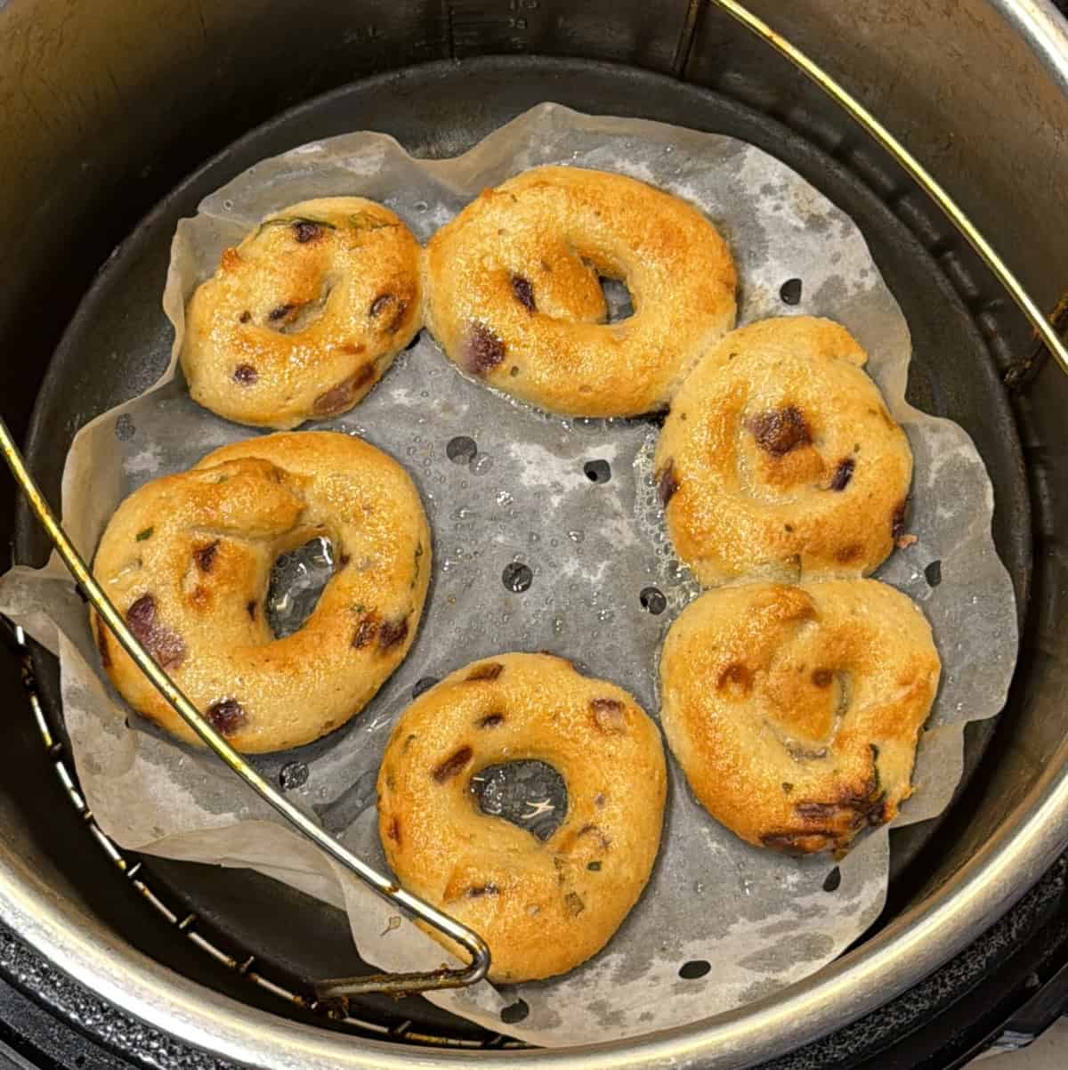 Instant medu vadas beginning to cook in the air fryer basket.