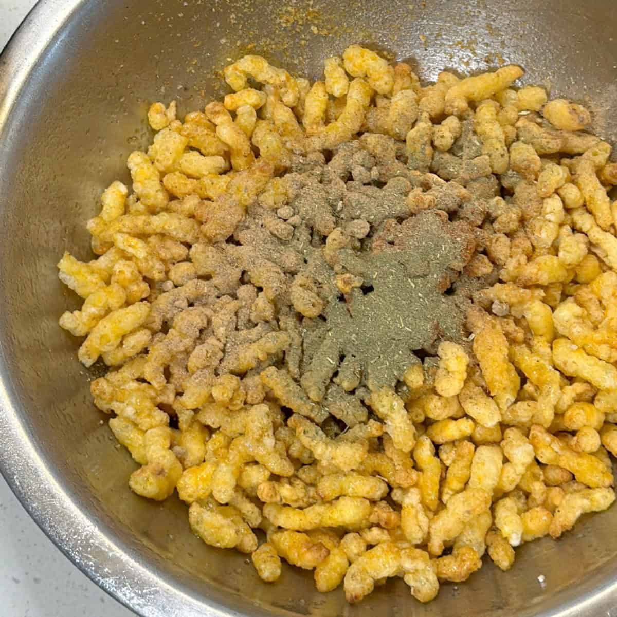 Oil and seasoning added to puffed corn before air frying