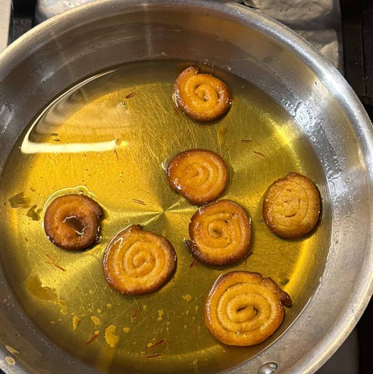 Finished air fryer jalebi soaking in warm sugar syrup
