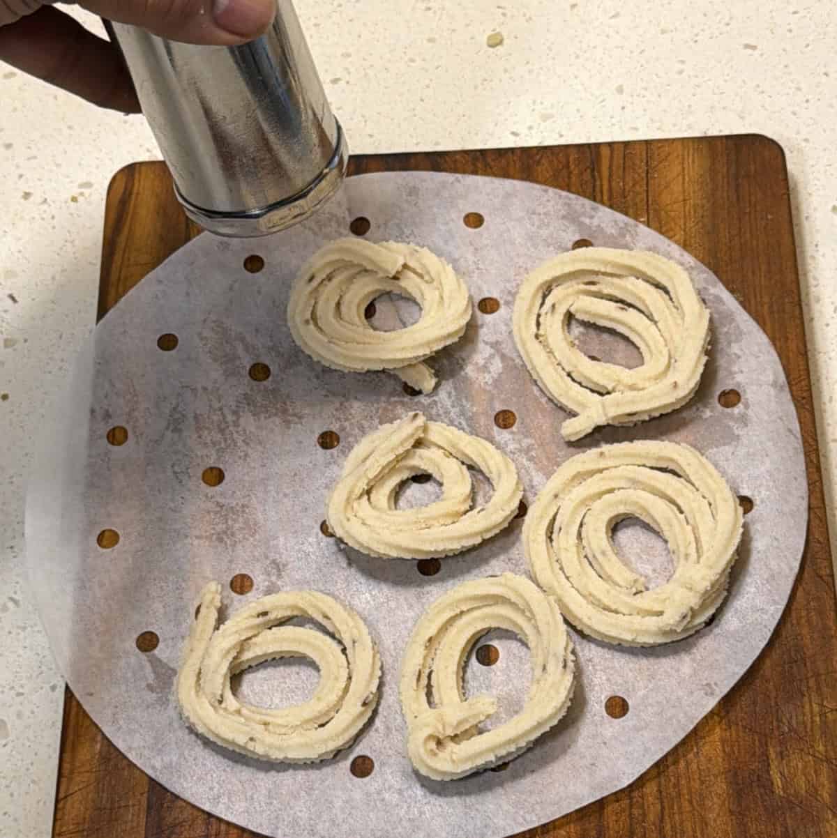Murukku press shaping dough into star-ridged chakli spirals