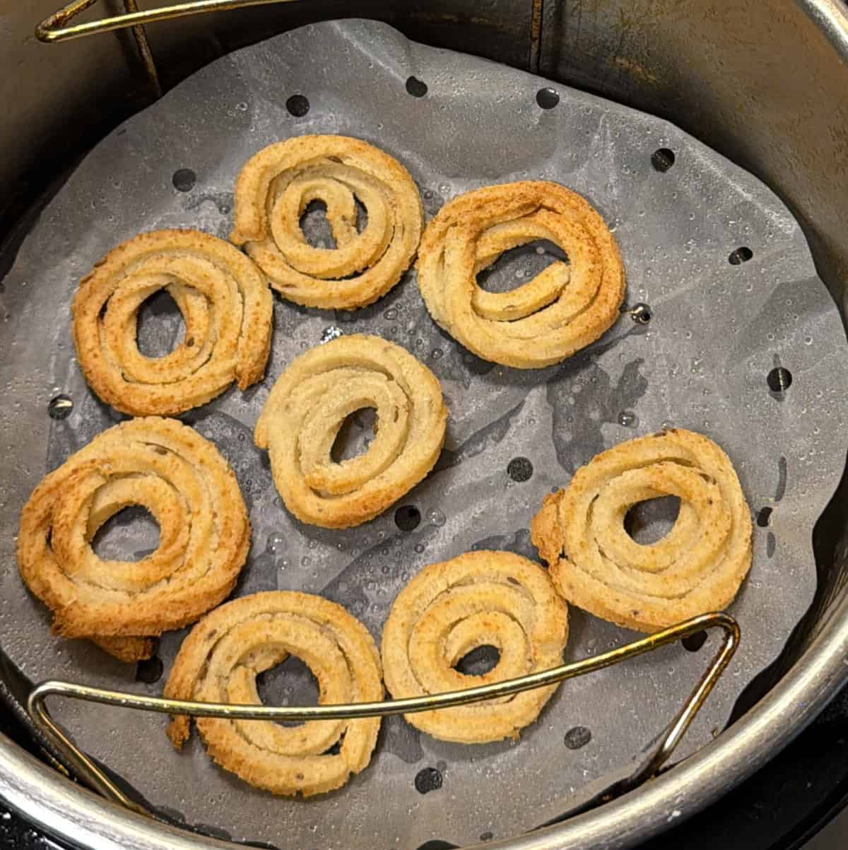 Chakli spirals turning golden during air frying