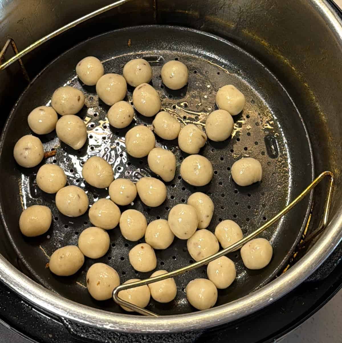 Small raw seedai balls tossed with oil in an air fryer tray