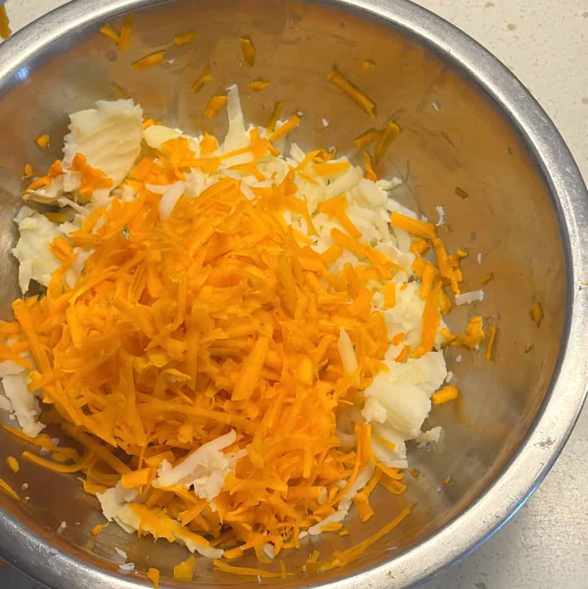 Raw grated carrot added to boiled potatoes