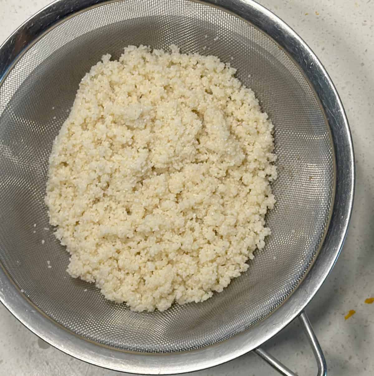 Soaked barnyard millet draining in a fine mesh sieve