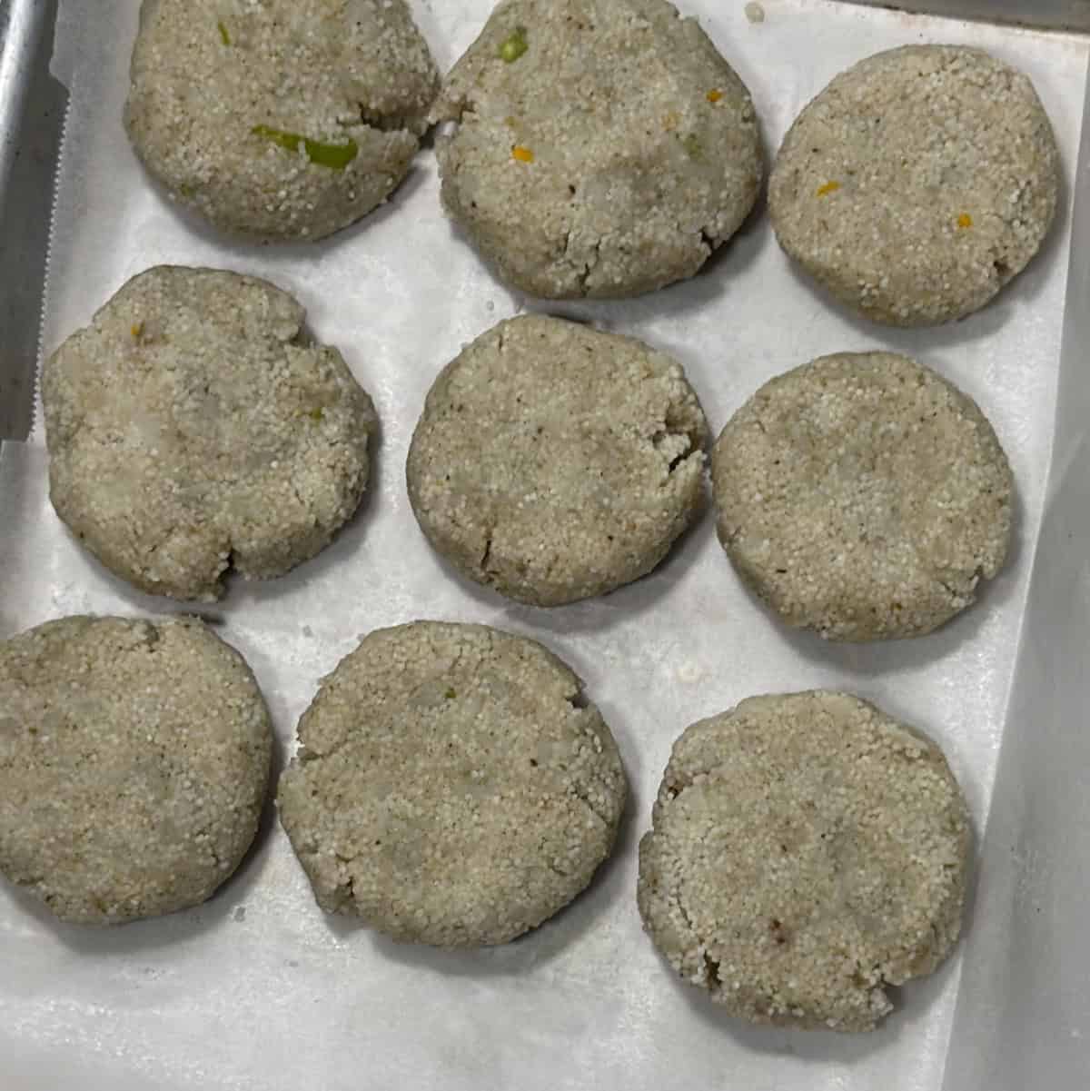 Shaped barnyard millet cutlets on a lined tray before freezing