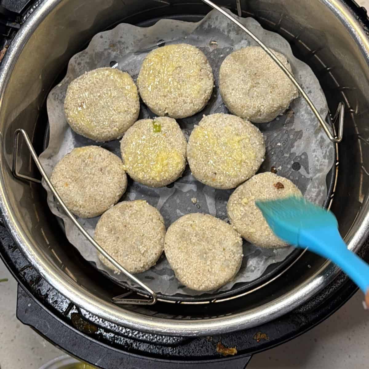 Frozen millet cutlets brushed with oil in an air fryer basket